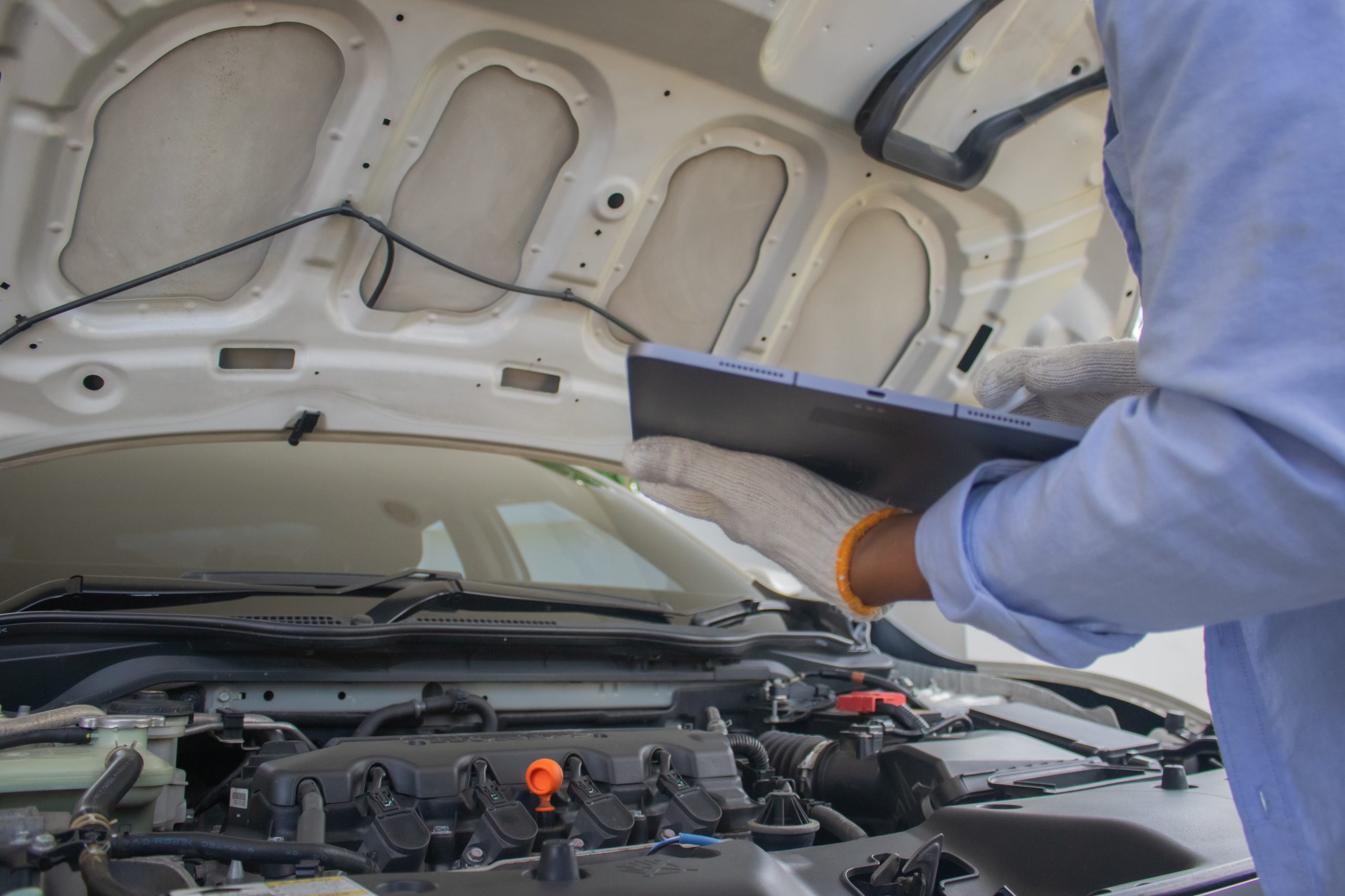 A technician checking under the bonnet of a newer vehicle